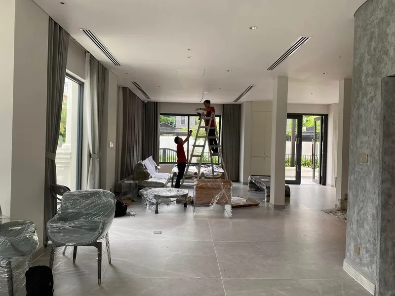 Đội ngũ thi công KTAA HOUSE lắp đặt đèn trần trong biệt thự với nội thất đang hoàn thiện